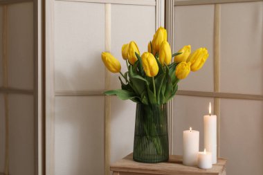 Mumları ve çiçekleri vazoda yakmak oturma odasındaki katlanan perdenin yanındaki masada, yakın plan