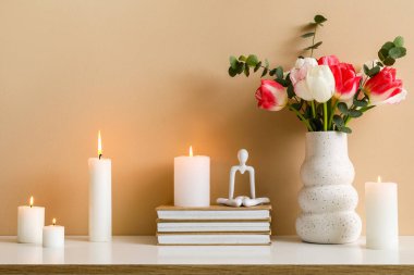 Odadaki bej duvarın yanındaki çekmecelerde mumlar, kitaplar ve çiçekler yakılıyor.