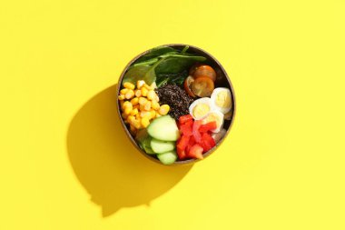 Sarı arka planda sebzeli sağlıklı kinoa kasesi.