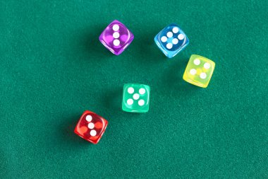 Yeşil arkaplanda farklı oyun zarları, yakın plan