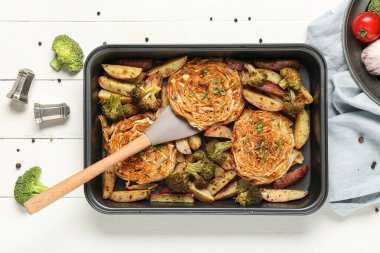 Beyaz ahşap arka planda lezzetli sebzeli fırın tepsisi, yakın plan.