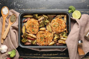 Siyah ahşap arka planda lezzetli sebzelerle pişirme tepsisi, yakın plan.