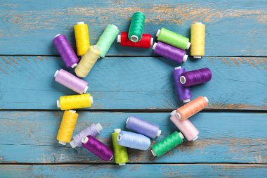 Mavi ahşap arka planda renkli iplik makaralarından yapılmış çerçeve