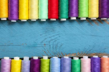 Mavi ahşap arka planda renkli iplik makaralarından yapılmış çerçeve