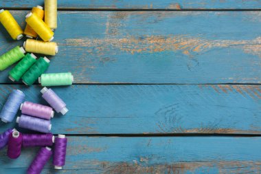 Mavi ahşap arkaplanda renkli iplik makaraları
