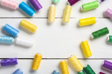 Beyaz ahşap arka planda renkli iplik makaralarından yapılmış çerçeve