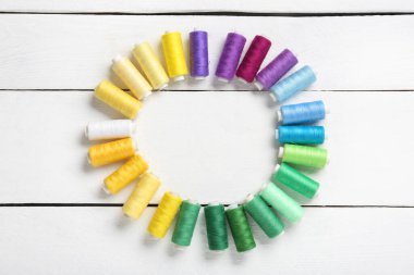 Beyaz ahşap arka planda renkli iplik makaralarından yapılmış çerçeve