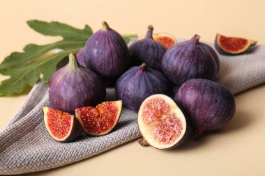 Bej arka planda taze incir ve yaprak, yakın plan.