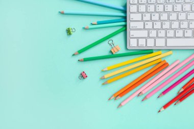 Klavye ve turkuaz arka planda farklı kalemlerle grafik tasarımcısının çalışma yeri
