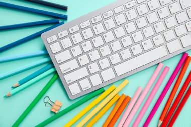 Klavye ve turkuaz arka planda farklı kalemlerle grafik tasarımcısının çalışma yeri