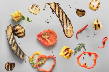 Gri arka planda uçuşan farklı lezzetli ızgara sebzeler.