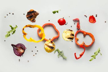 Gri arka planda uçuşan farklı lezzetli ızgara sebzeler.