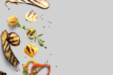 Gri arka planda uçuşan farklı lezzetli ızgara sebzeler.