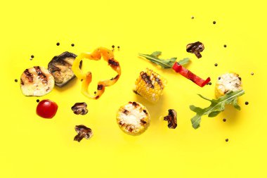 Sarı arka planda uçuşan farklı lezzetli ızgara sebzeler.