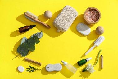 Ayak masajı için banyo malzemelerinden yapılmış çerçeve, yeşil dallar ve sarı arka planda çiçek.