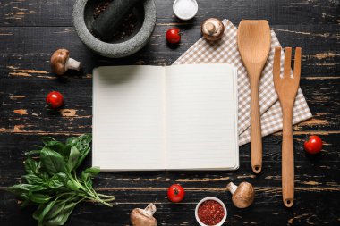 Siyah ahşap zemin üzerinde boş tarif defteri, baharatlar ve peçeteyle kompozisyon