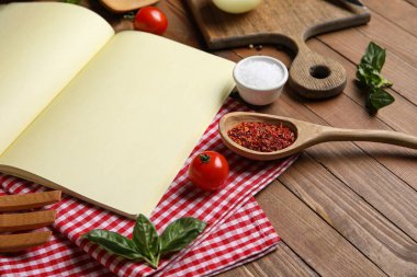 Ahşap zemin üzerinde boş tarif defteri, peçete ve malzeme içeren kompozisyon, yakın plan