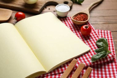 Ahşap zemin üzerinde boş tarif defteri, peçete ve malzeme içeren kompozisyon, yakın plan