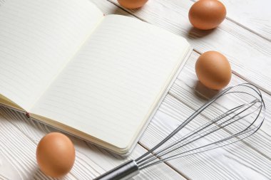 Boş tarif defteri, çırpma ve yumurta hafif ahşap arka plan, yakın plan