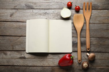 Boş tarif defteri, malzemeler ve ahşap zemin üzerinde ahşap çatal bıçak olan kompozisyon
