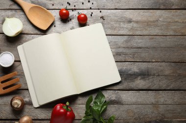 Boş tarif defteri, malzemeler ve ahşap zemin üzerinde ahşap çatal bıçak olan kompozisyon