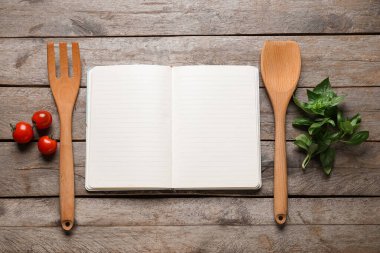 Boş tarif defteri, malzemeler ve ahşap zemin üzerinde ahşap çatal bıçak olan kompozisyon