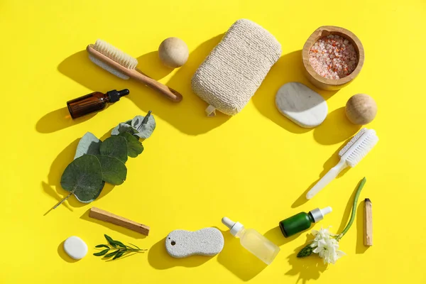 Ayak masajı için banyo malzemelerinden yapılmış çerçeve, yeşil dallar ve sarı arka planda çiçek.