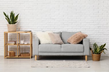 Raflama ünitesi, kanepe ve sansevieria çiçekleri odanın içindeki beyaz tuğla duvarın yanında.