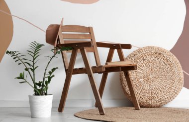 Renkli duvarın yanında sandalye, puf ve çiçek bulunan modern tarz bir oda.