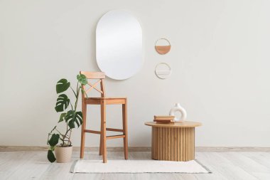 Sandalyesi, çiçekleri ve bej duvarın yanındaki masası olan modern tarz bir oda.