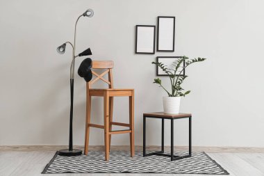 Beyaz duvarın yanında sandalye, masa ve zemin lambası olan modern tarz bir oda.