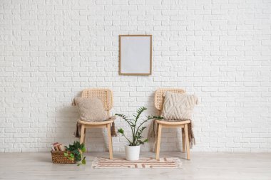 Modern odanın içindeki beyaz tuğla duvarın yanında yastıklı sandalyeler.