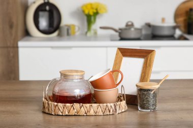 Mutfaktaki cam çaydanlıklı tepsi ve fincanlar, yakın plan.