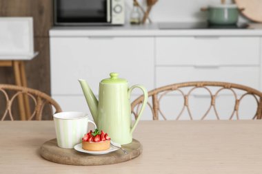 Yeşil çaydanlık, fincan ve lezzetli kek mutfaktaki masada, yakın plan.