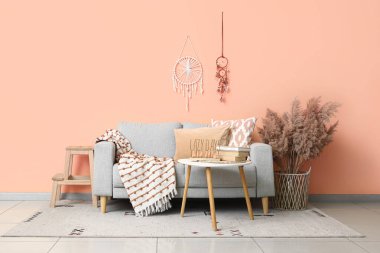 Rahat bir kanepe, masa ve vazo, mercan duvarının yanında otlar, oturma odası.