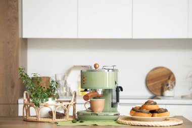 Modern kahve makinesi, tatlı çörekler ve mutfaktaki masa bitkisi.