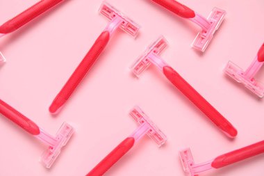 Pembe arka planda tek kullanımlık tıraş bıçakları olan kompozisyon, yakın plan.