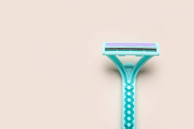 Bej arka planda tek kullanımlık tıraş bıçağı, yakın plan.