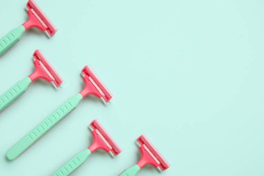 Turkuaz arka planda tek kullanımlık tıraş bıçakları, yakın plan.