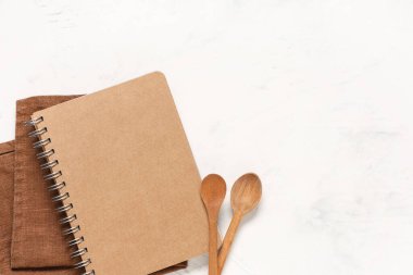 Beyaz arka planda kaşık ve peçeteli boş tarif kitabı