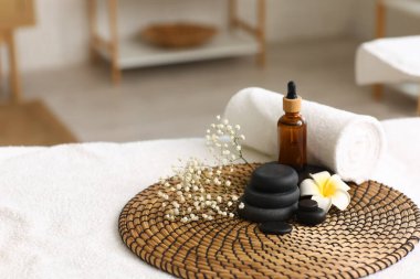 Salondaki kanepede havlu, tesisat çiçeği ve kozmetik ürünlerle kaplıca taşları.