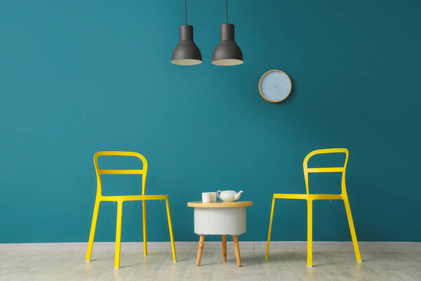 Chairs and table near blue wall in interior of modern room
