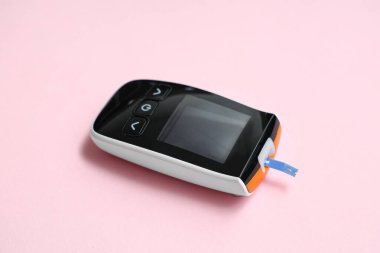 Pembe arka planda dijital glukometre, yakın plan