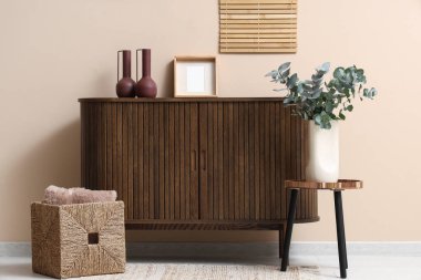 Okaliptüs dallarıyla dolu vazo bej duvarın yanındaki odada.