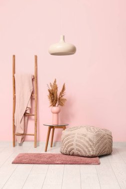 Interior of room with pouf, stepladder and table near coral wall