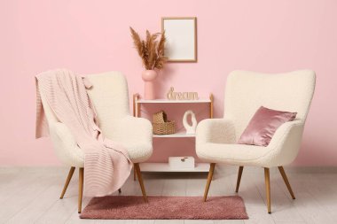 Interior of room with shelving unit and armchairs near coral wall
