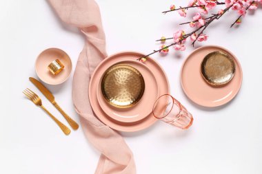 Altın çatal bıçak takımları ve gri arka planda çiçek açan dallarıyla güzel bir masa.