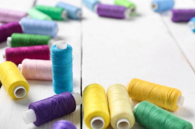 Beyaz ahşap arkaplanda renkli iplik makaraları