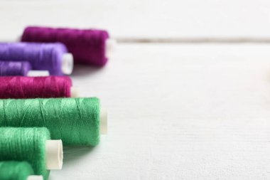 Beyaz ahşap arkaplanda renkli iplik makaraları