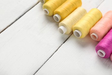 Beyaz ahşap arkaplanda renkli iplik makaraları